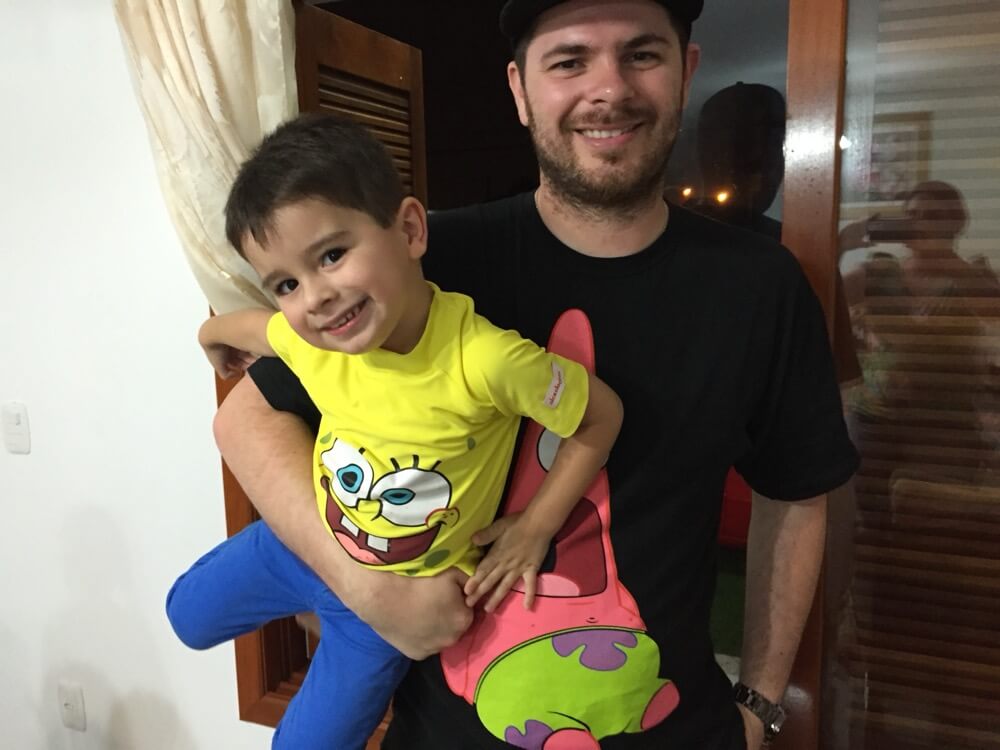 Deds pequeno, de camiseta do Bob Esponja, no colo do Tio Baboo