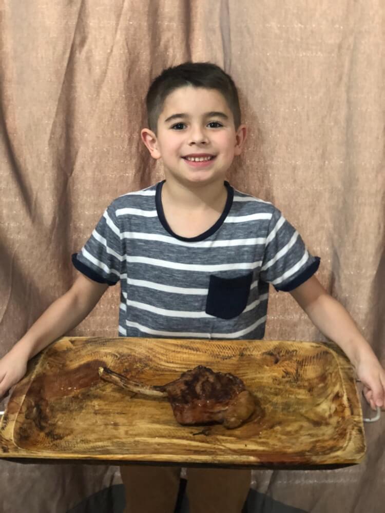 Deds segurando uma tábua de madeira com um tomahawk grelhado