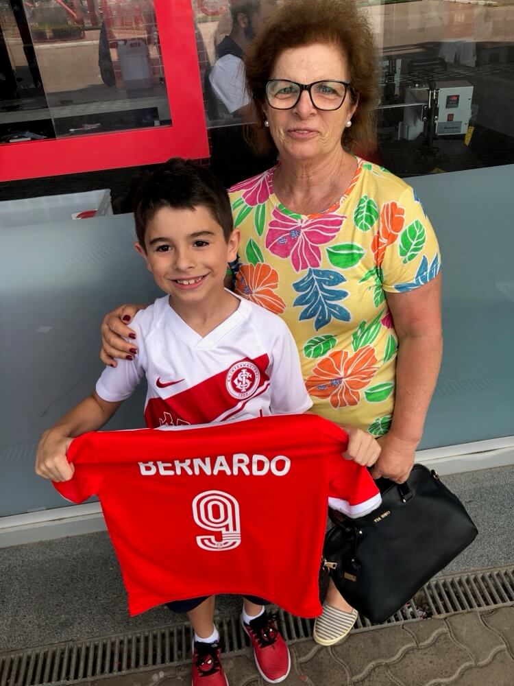 Deds com a avó, segurando a camisa personalizada do Internacional com o nome dele