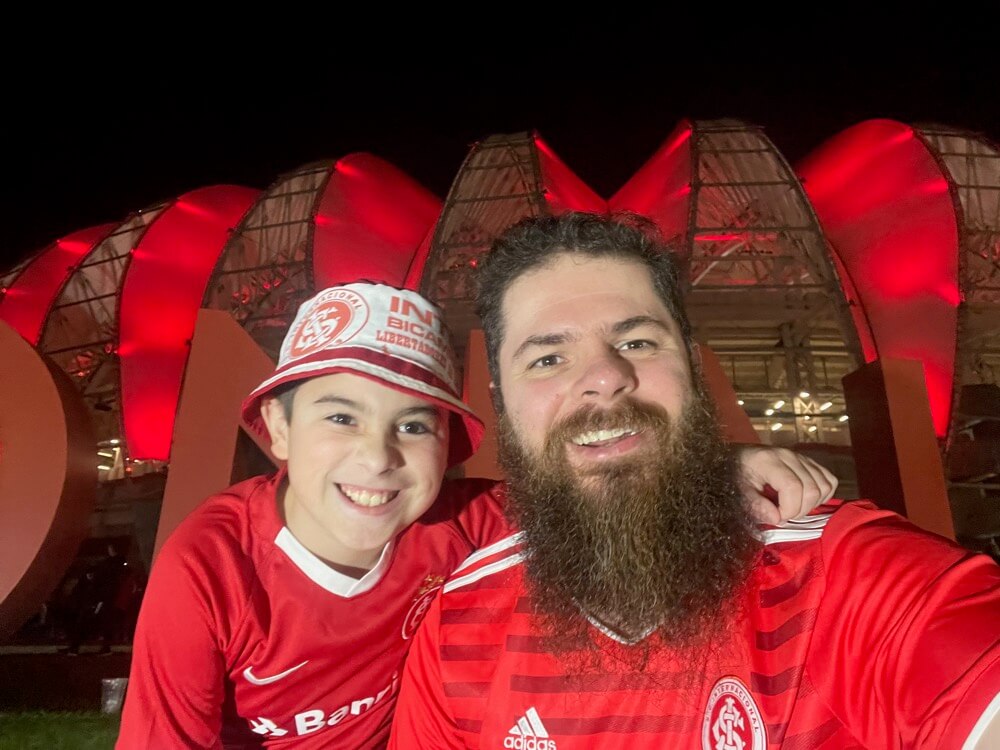 Deds e o Tio Baboo sorrindo em frente à fachada iluminada do Beira-Rio à noite